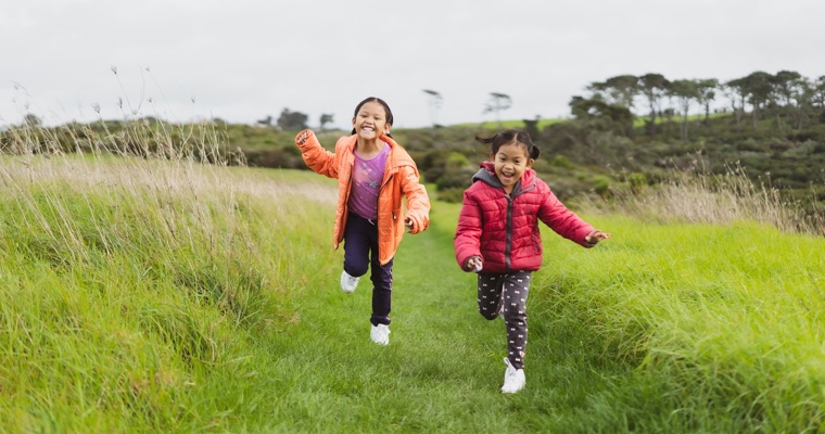 Two girls running through a field
